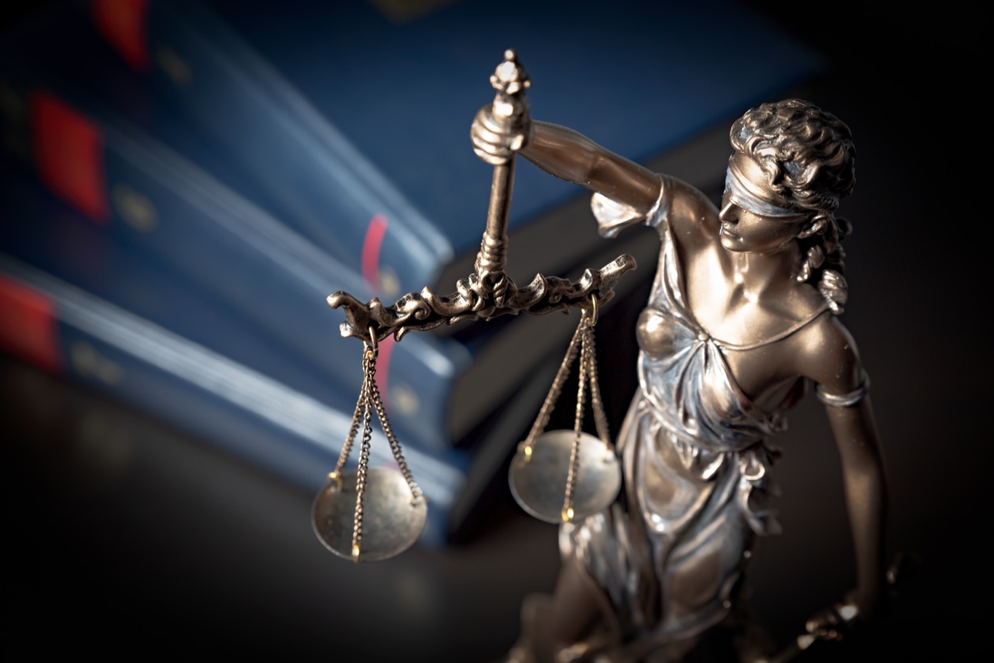 Lady Justice statue brass scales law books motion blur
