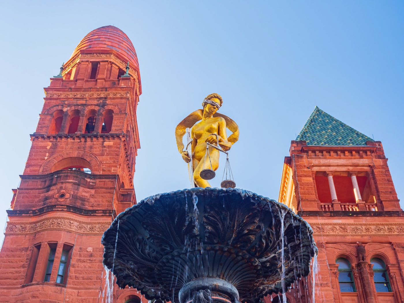 Red sandstone towers golden statue fountain blue sky Romanesque building, San Antonio